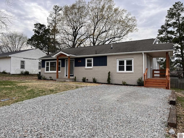 ranch-style home featuring driveway, stucco siding, and roof with shingles