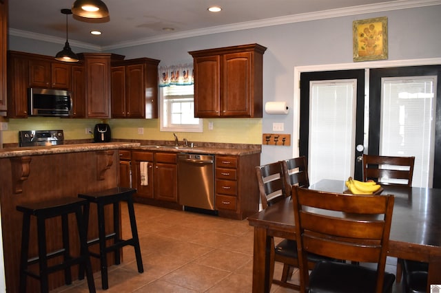 kitchen featuring a sink, appliances with stainless steel finishes, light tile patterned floors, dark countertops, and ornamental molding