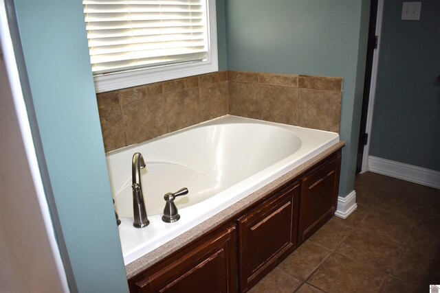 bathroom featuring tile patterned floors, baseboards, and a bath