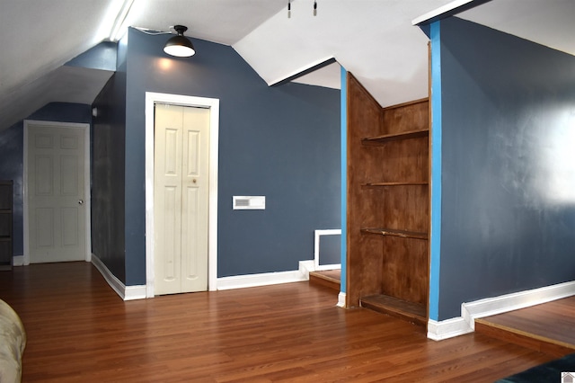 additional living space with baseboards, wood finished floors, and vaulted ceiling