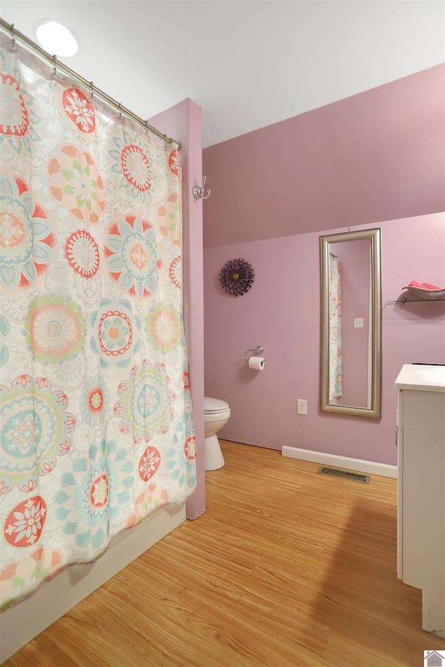 full bath featuring toilet, vanity, shower / bath combo, wood finished floors, and visible vents