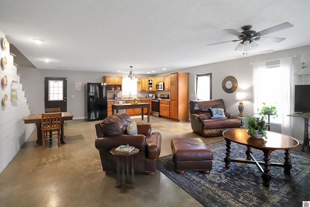 living room featuring finished concrete flooring, ceiling fan, and a healthy amount of sunlight