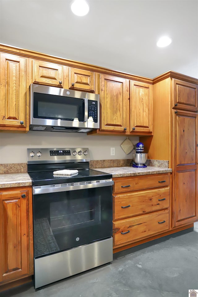 kitchen featuring light countertops, concrete flooring, recessed lighting, appliances with stainless steel finishes, and brown cabinetry