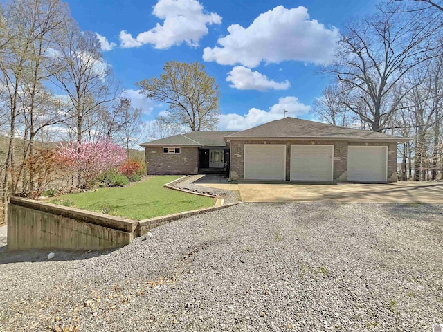 view of front of house featuring brick siding, a front yard, driveway, and an attached garage
