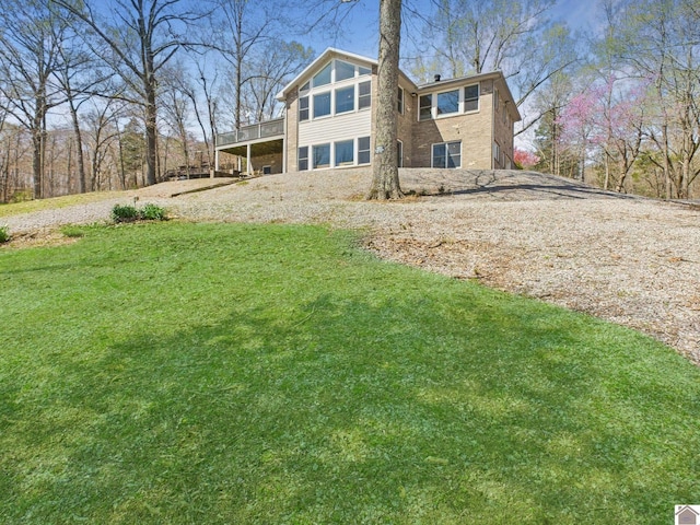 rear view of property with gravel driveway and a lawn