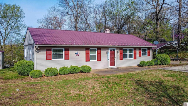 single story home featuring a front lawn, a chimney, a patio, and metal roof