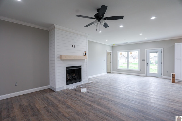 unfurnished living room featuring wood finished floors, ornamental molding, baseboards, a large fireplace, and ceiling fan