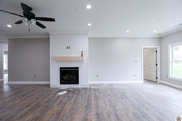 unfurnished living room with wood finished floors, a fireplace, baseboards, ornamental molding, and visible vents