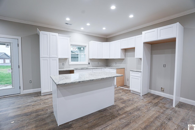 kitchen with dark wood-type flooring, a center island, white cabinetry, and crown molding
