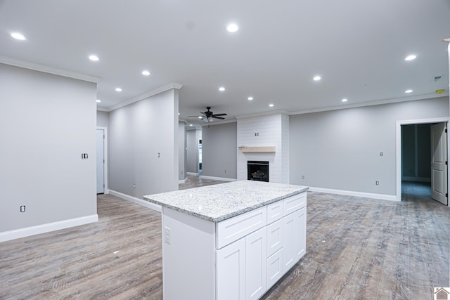 kitchen featuring open floor plan, a kitchen island, ceiling fan, and crown molding