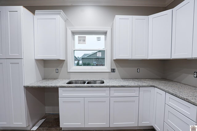 kitchen featuring light stone counters, a sink, white cabinetry, and ornamental molding