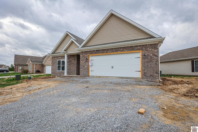 view of front facade featuring gravel driveway, brick siding, and a garage