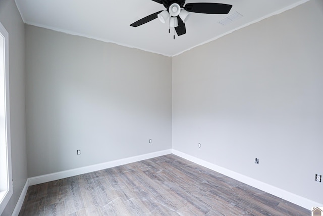 spare room with visible vents, baseboards, wood finished floors, ceiling fan, and crown molding