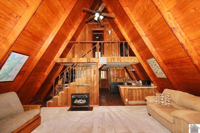 living area with wooden ceiling, wooden walls, a ceiling fan, stairs, and vaulted ceiling with beams