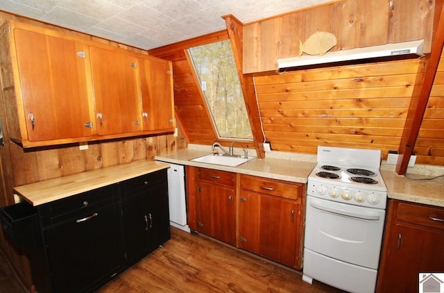 kitchen featuring white appliances, wooden walls, light countertops, under cabinet range hood, and a sink