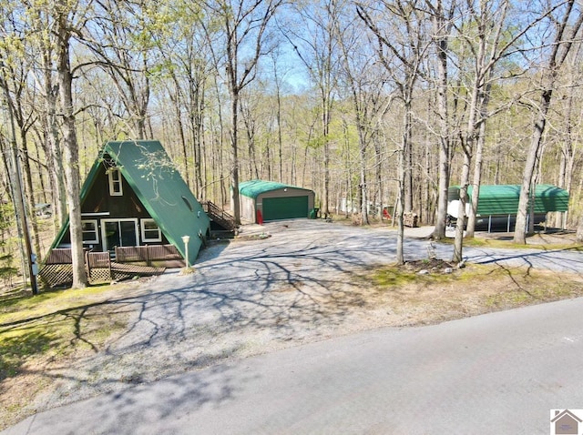 exterior space with a view of trees, a detached garage, and an outdoor structure