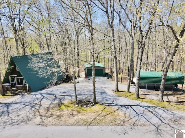 view of yard featuring a wooded view, a detached garage, and an outdoor structure