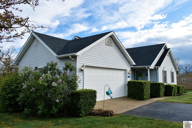 view of home's exterior with roof with shingles, aphalt driveway, and a garage