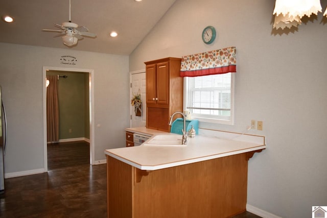 kitchen featuring baseboards, dishwasher, a sink, light countertops, and brown cabinetry