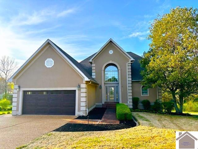 traditional-style house with an attached garage, driveway, and stucco siding