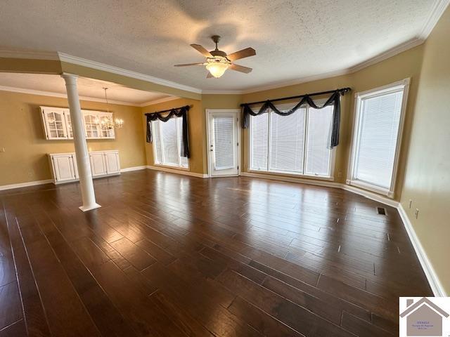 unfurnished living room featuring a textured ceiling, a wealth of natural light, decorative columns, and ceiling fan with notable chandelier