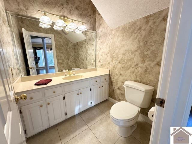 bathroom featuring vanity, tile patterned flooring, vaulted ceiling, toilet, and baseboards