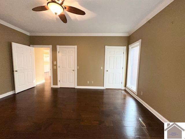spare room featuring dark wood-type flooring, ceiling fan, baseboards, and ornamental molding