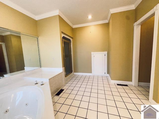 bathroom featuring tile patterned flooring, a jetted tub, baseboards, and ornamental molding