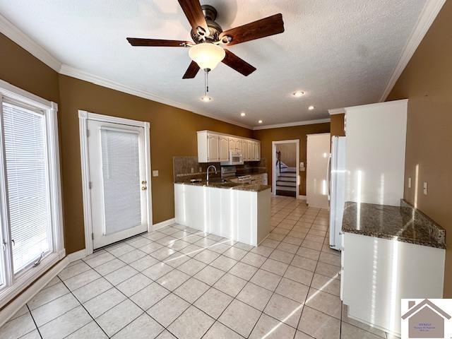kitchen with crown molding, decorative backsplash, white appliances, and a peninsula