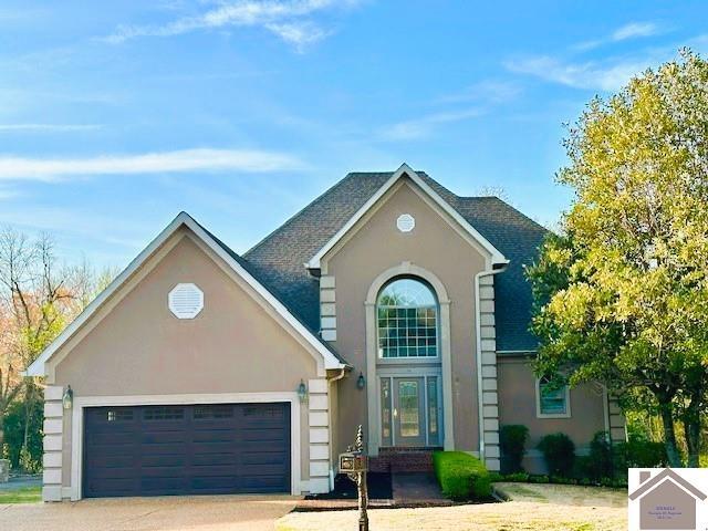 traditional home with concrete driveway, a garage, and stucco siding