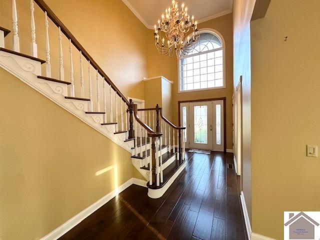 entrance foyer featuring stairway, a notable chandelier, baseboards, and a towering ceiling