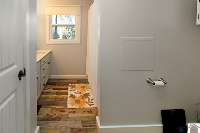 full bathroom featuring vanity, baseboards, and wood finished floors