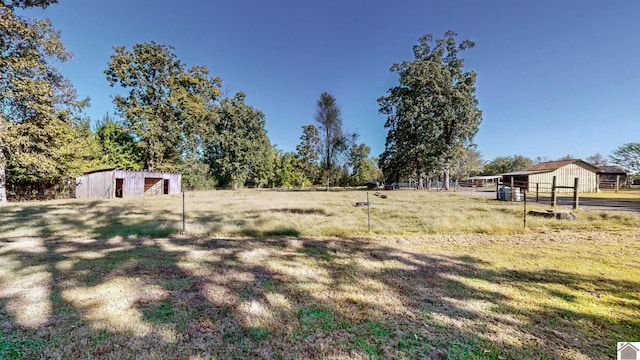 view of yard featuring an outbuilding, a pole building, and fence