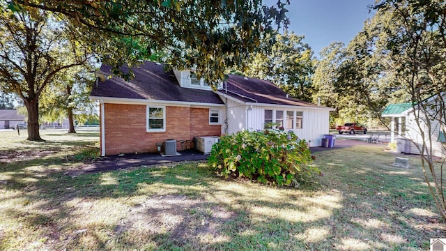back of house featuring a yard, central AC unit, and brick siding