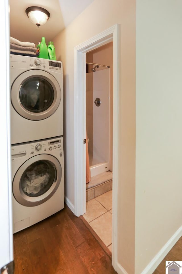 washroom with laundry area, stacked washer and dryer, and wood finished floors
