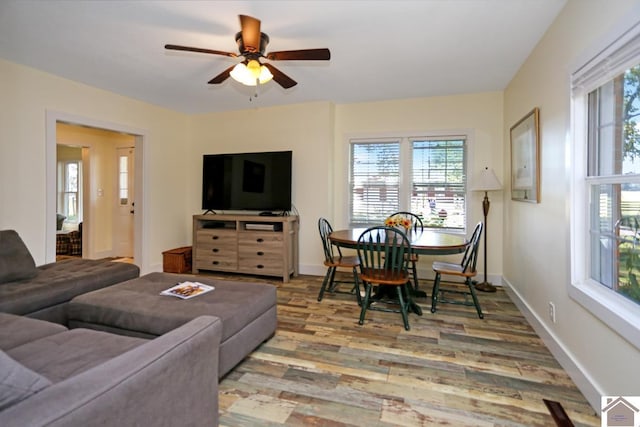 living area with a wealth of natural light, a ceiling fan, wood finished floors, and baseboards