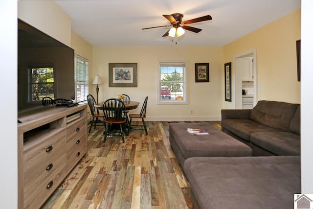 living room featuring light wood-style flooring, a wealth of natural light, a ceiling fan, and baseboards