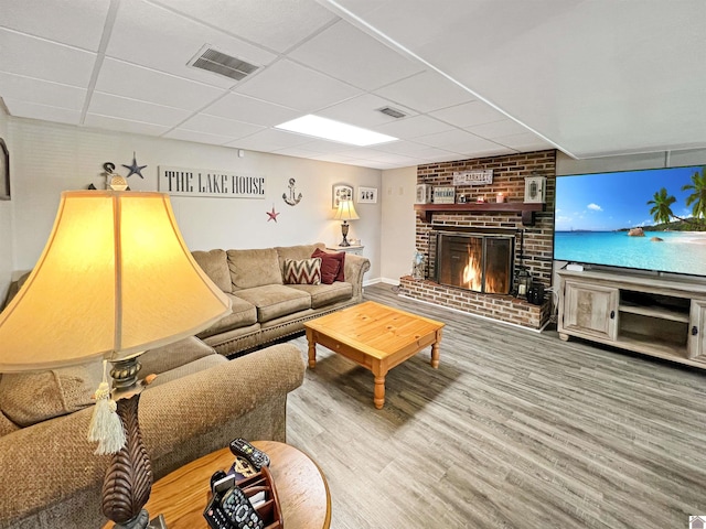 201 Blue River Rd, Cadiz, KY 42211 - living room featuring visible vents, a brick fireplace, a drop ceiling, and wood finished floors