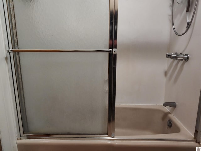 bathroom with bath / shower combo with glass door