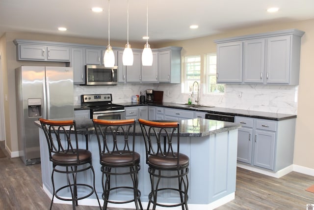 kitchen featuring backsplash, appliances with stainless steel finishes, a sink, and dark wood-style floors
