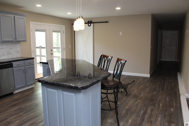 kitchen featuring dark wood finished floors, tasteful backsplash, stainless steel dishwasher, and gray cabinetry