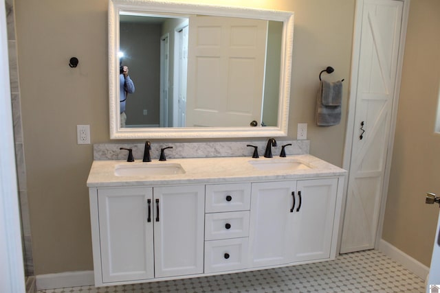 bathroom featuring baseboards, tile patterned floors, a sink, and double vanity