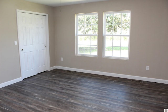 spare room with baseboards, dark wood-style flooring, and visible vents