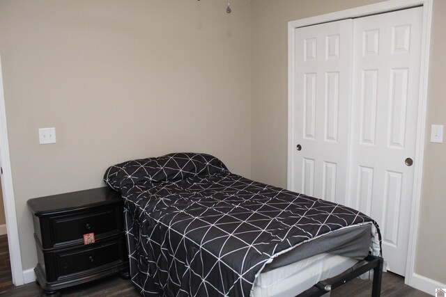 bedroom featuring baseboards, a closet, and dark wood-style flooring