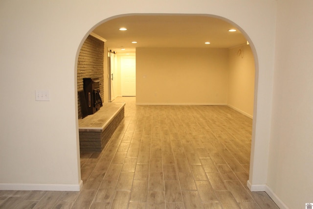 unfurnished living room featuring baseboards, recessed lighting, a fireplace, and light wood-type flooring