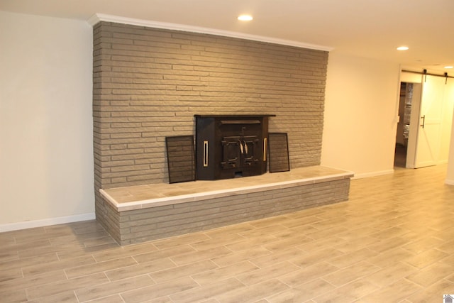details featuring a barn door, recessed lighting, wood finished floors, baseboards, and a fireplace