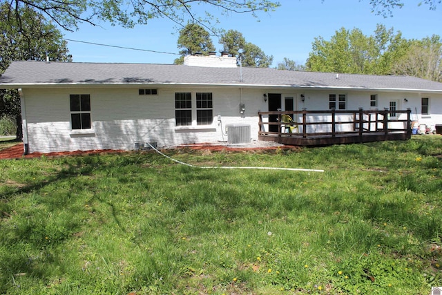 rear view of house with a lawn, a chimney, cooling unit, and a deck