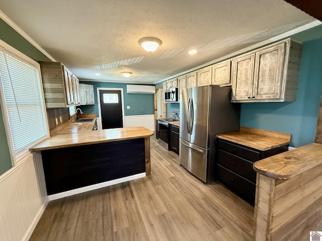 kitchen with light wood-style floors, a sink, a textured ceiling, and appliances with stainless steel finishes
