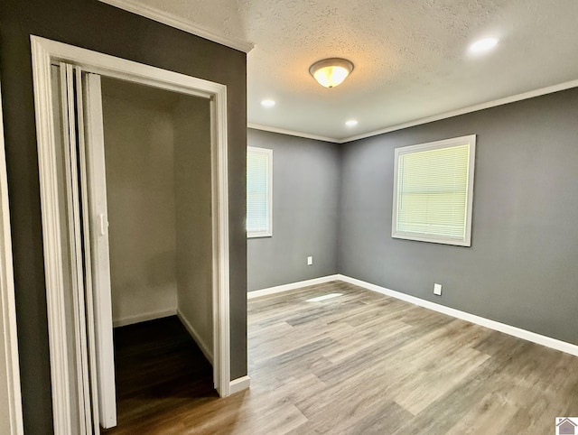 unfurnished bedroom featuring baseboards, crown molding, wood finished floors, and a textured ceiling