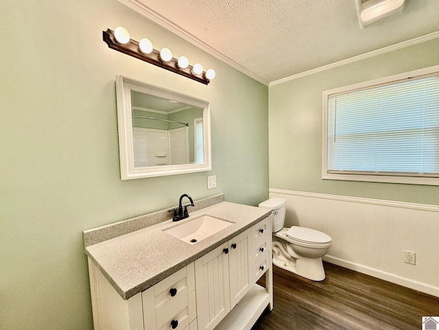 full bathroom featuring a textured ceiling, toilet, wood finished floors, vanity, and ornamental molding